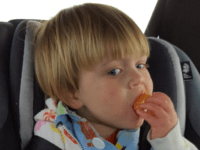 child eating in car seat