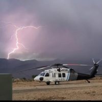 helicopter on ground with ligtning in mountain background